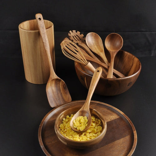 Wooden kitchen utensils arranged near a breakfast bowl on a dark table
