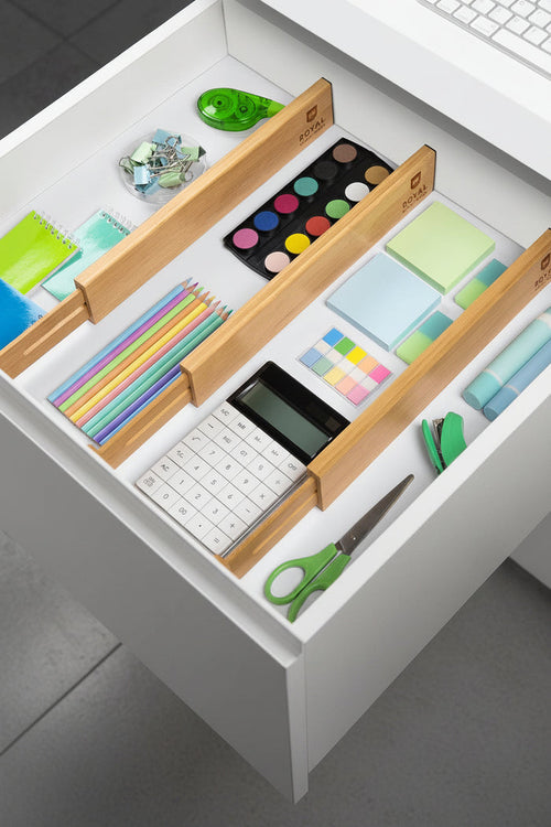 Adjustable bamboo drawer dividers organizing office supplies inside a white desk drawer