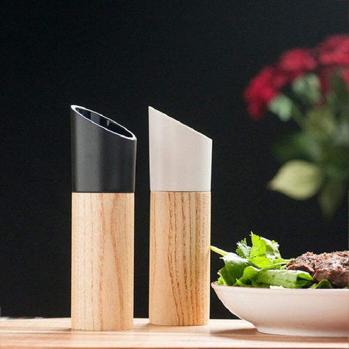 Black and white adjustable wooden salt and pepper grinders displayed beside a salad