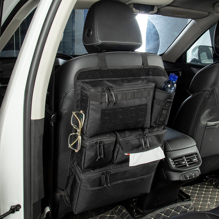 Black car seat back organizer installed behind a vehicle seat with multiple storage pockets, bottle holder, and utility loops